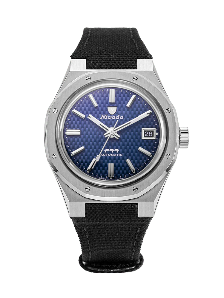 A silver Nivada Grenchen F77 automatic watch, model 69001A77-BC, featuring a blue textured dial, black strap, and date display at 3 o’clock.