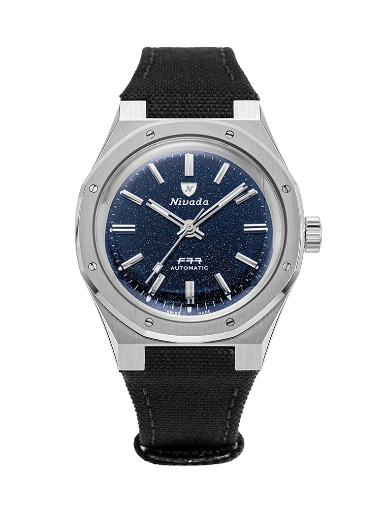 A silver Nivada Grenchen wristwatch, model 68010A77-BC, with a dark blue glittery dial and a black fabric strap is displayed on a white background.