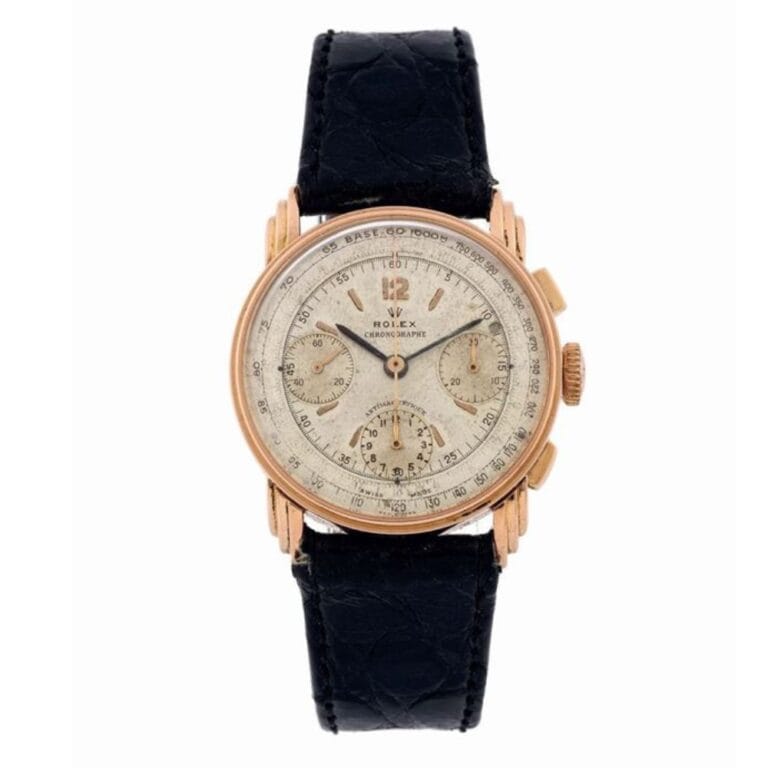 A vintage Rolex 3835 chronograph watch with a gold case, cream dial, and black leather strap.