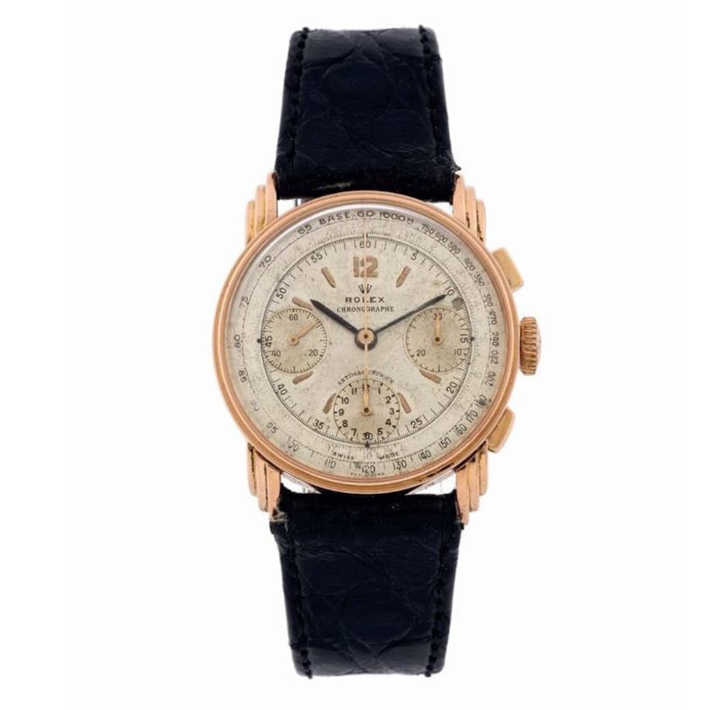 A vintage Rolex 3835 chronograph watch with a gold case, cream dial, and black leather strap.