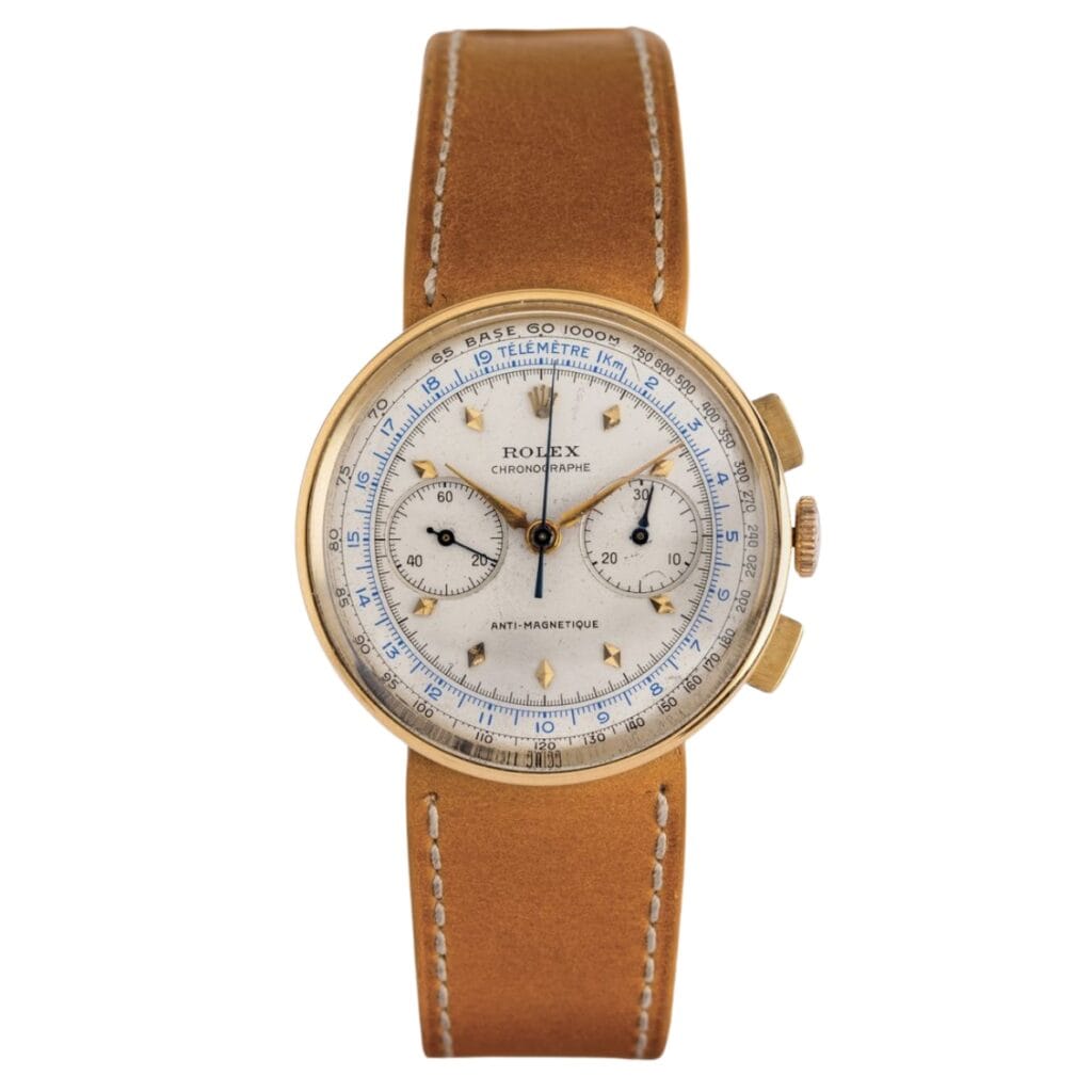 A vintage Rolex 3233 chronograph watch with a tan leather strap and a gold case.