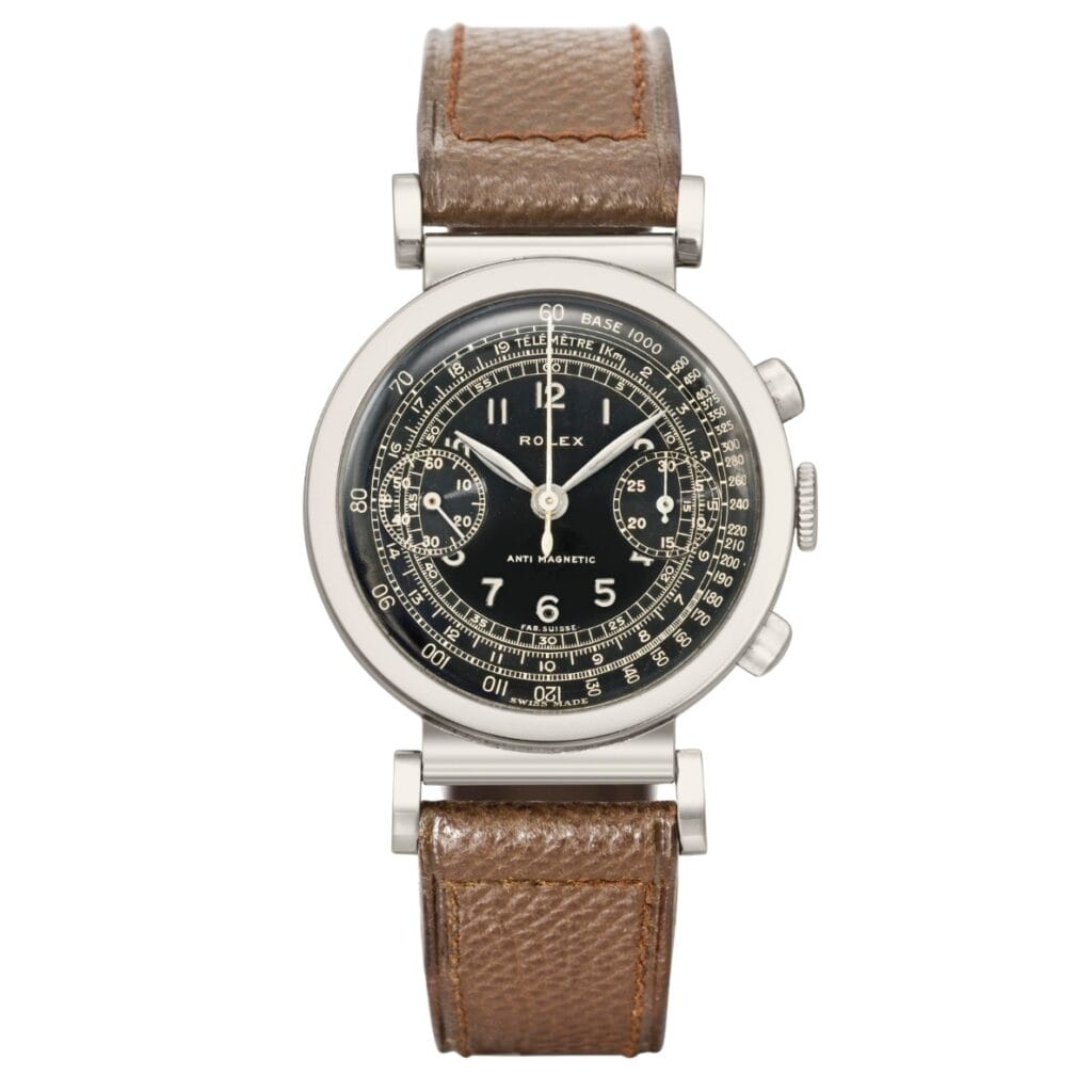 A vintage Rolex Chronograph 2918 watch with a black dial, silver case, and brown leather strap.