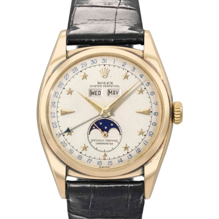 A gold Rolex watch with a moonphase, day, date, and month display, and a black leather strap.