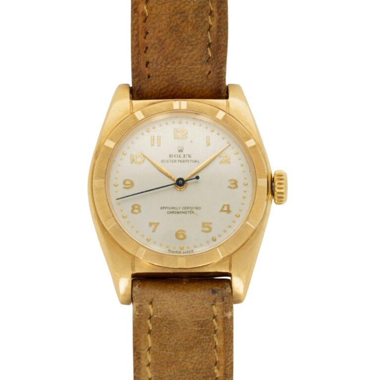 A vintage gold Rolex Oyster Perpetual 6011 watch with a brown leather strap and a white dial, showing the time as 3:53.