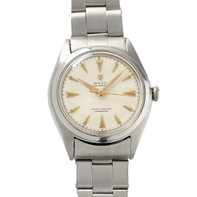 Vintage Rolex Oyster Perpetual 5028 watch with a silver bracelet and a cream dial featuring elegant gold hour markers.
