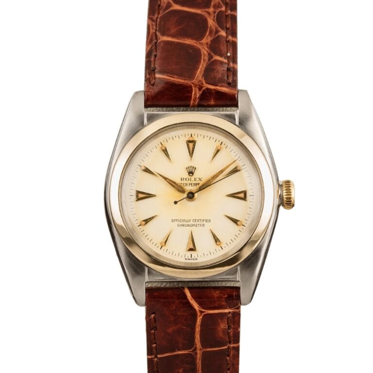 Vintage Rolex Oyster Perpetual watch with a cream dial, gold markers, and a brown leather strap. Model 5010.