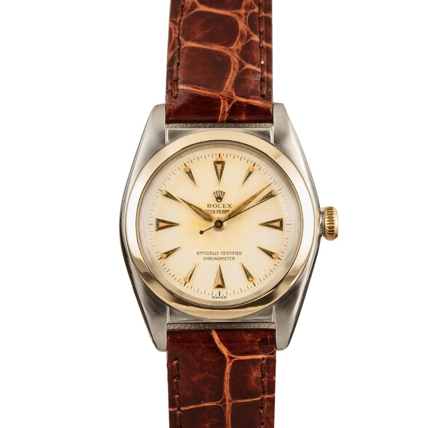 Vintage Rolex Oyster Perpetual watch with a cream dial, gold markers, and a brown leather strap. Model 5010.