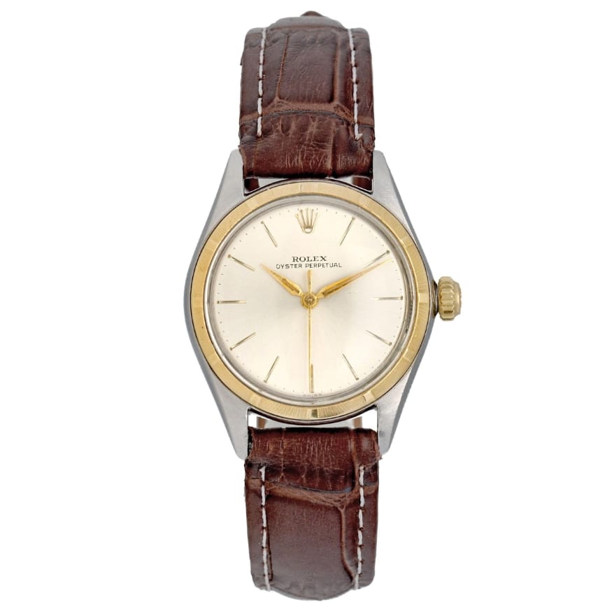 A classic Rolex Oyster Perpetual 5007 wristwatch featuring a brown leather strap and a silver and gold round face that elegantly displays the time.