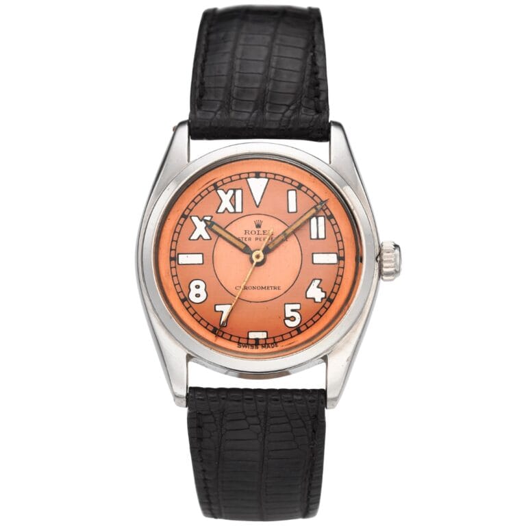 A silver Rolex Cioccolatone 6031 wristwatch with a black leather strap and an orange dial featuring large white numerals.
