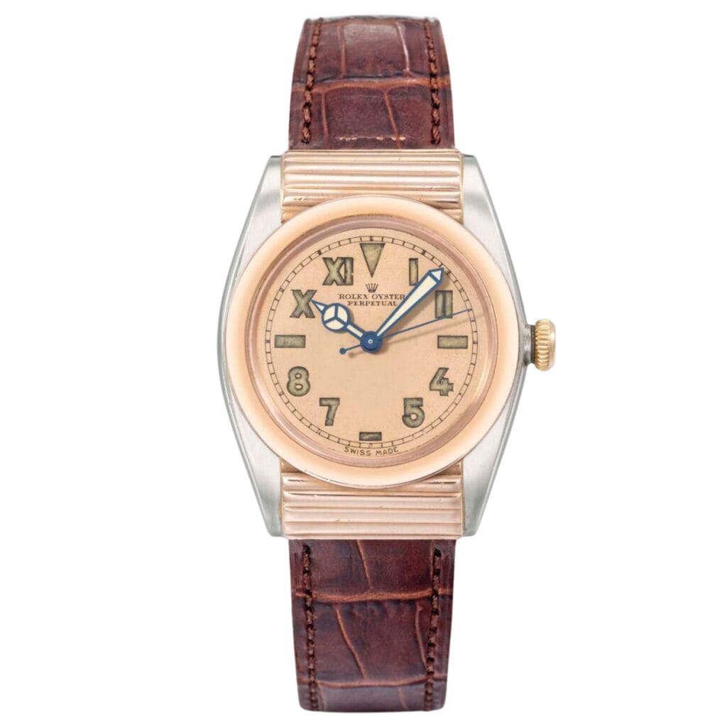A vintage Rolex Oyster Perpetual watch with a brown leather strap and a gold-tone dial displaying Roman and Arabic numerals.