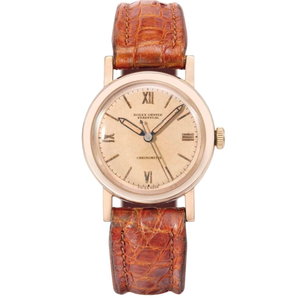 A vintage Rolex Oyster Perpetual wristwatch with a brown leather strap and a beige dial displaying Roman numerals.