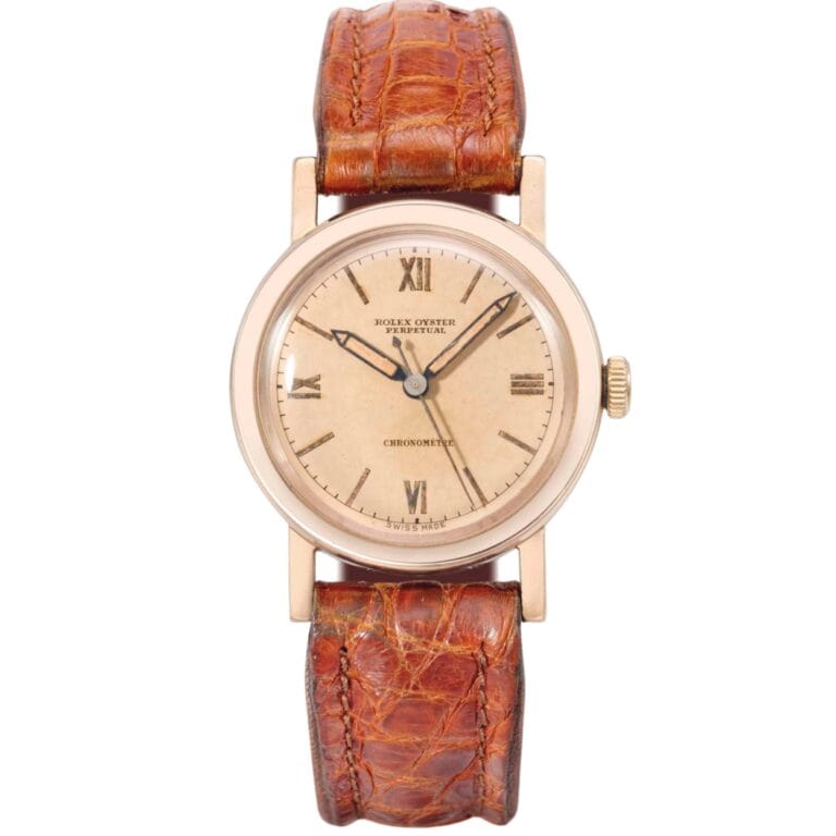 A vintage Rolex Oyster Perpetual wristwatch with a brown leather strap and a beige dial displaying Roman numerals.