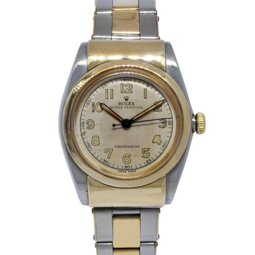 A two-tone Rolex Oyster Perpetual wristwatch with a silver and gold band, featuring a round face that displays gold numbers and hands.