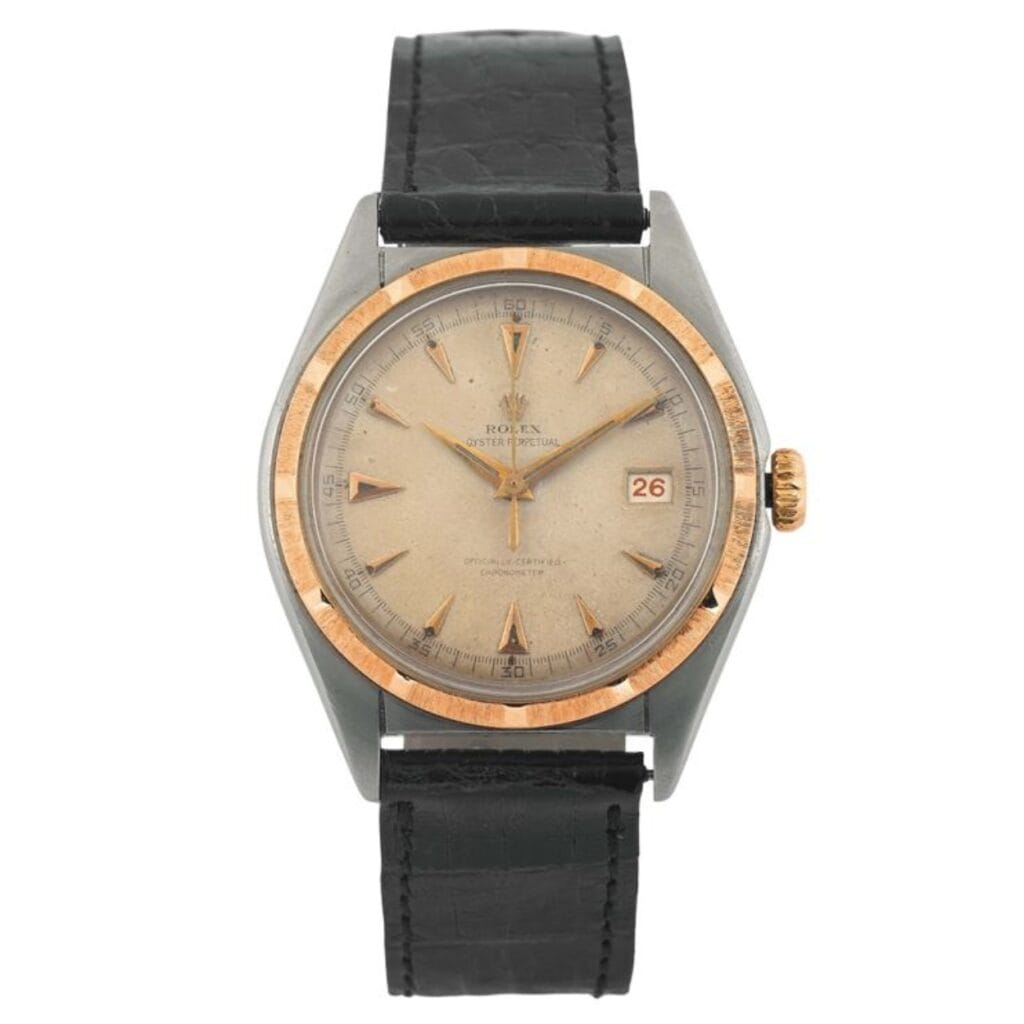 Vintage Rolex Oyster Perpetual wristwatch, model 6031, featuring a round dial, gold bezel, and black leather strap with date display at 3 o’clock.