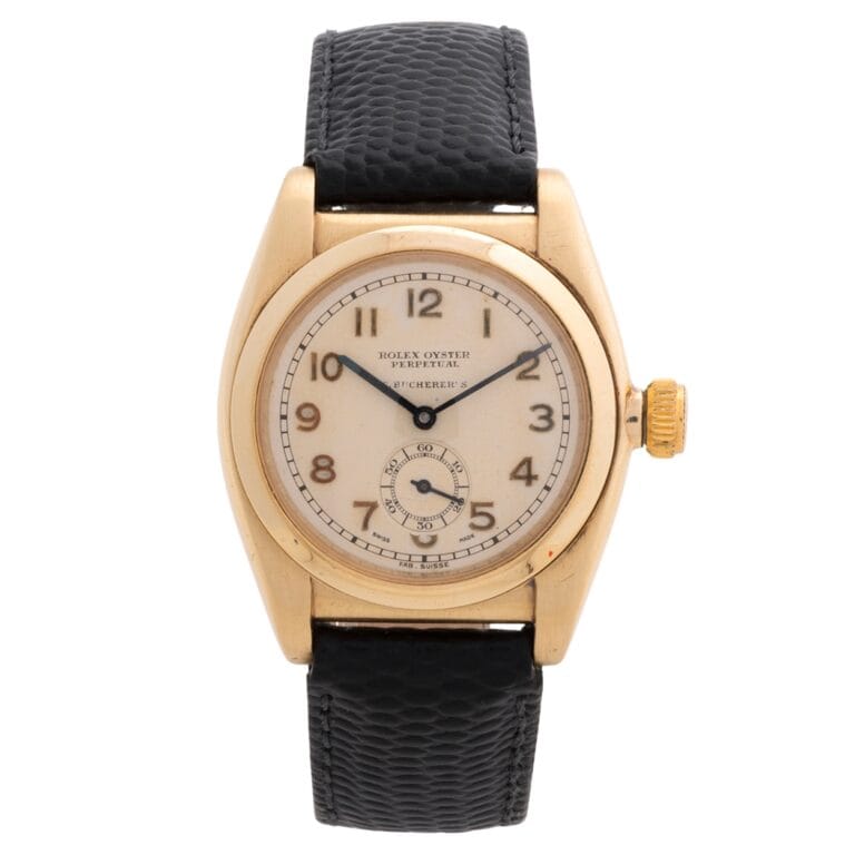 Vintage Rolex Oyster Perpetual wristwatch with a gold case, cream dial, and black textured leather strap.