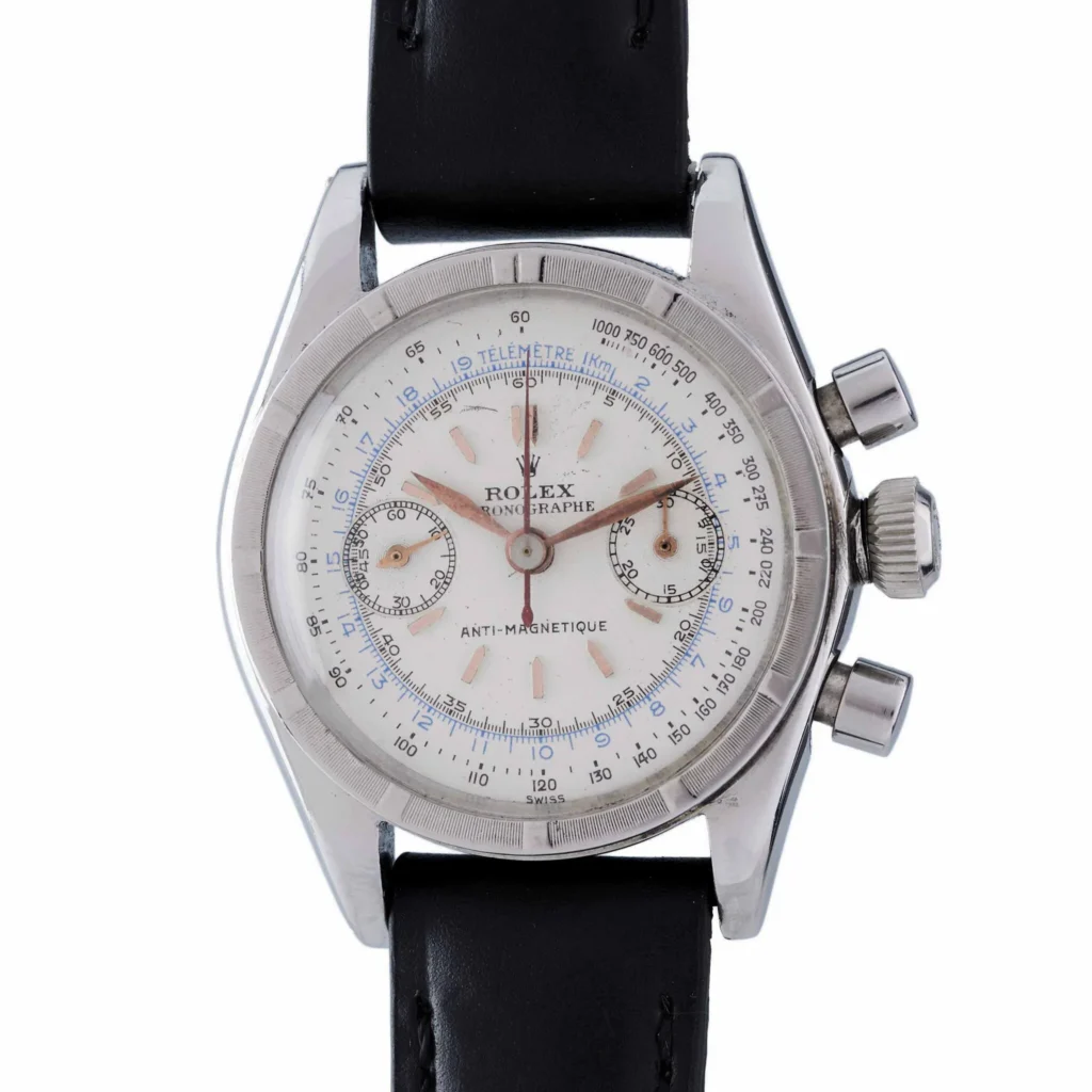 A vintage Rolex chronograph 3181 watch with a white dial, black strap, and silver case.