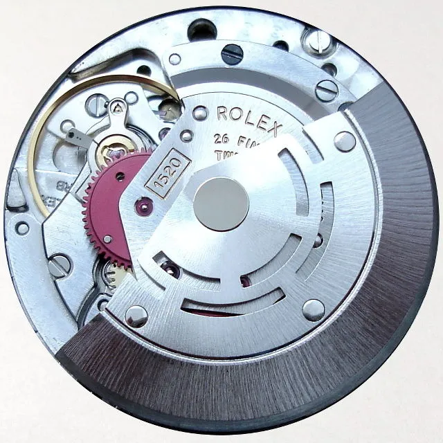 Close-up of a Rolex watch movement showing gears, metal parts, and the engraved ROLEX and 1520 model number.