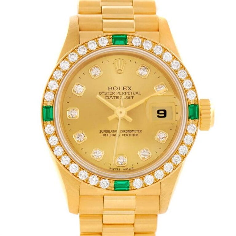 Gold Rolex Datejust 79078 watch with diamond and emerald bezel, gold dial, and date display at 3 o’clock.