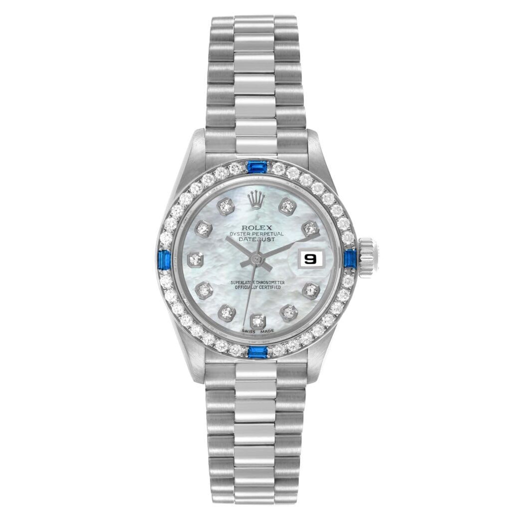 A silver Rolex Datejust 69089 watch featuring a diamond and sapphire bezel, mother-of-pearl dial, and date display.