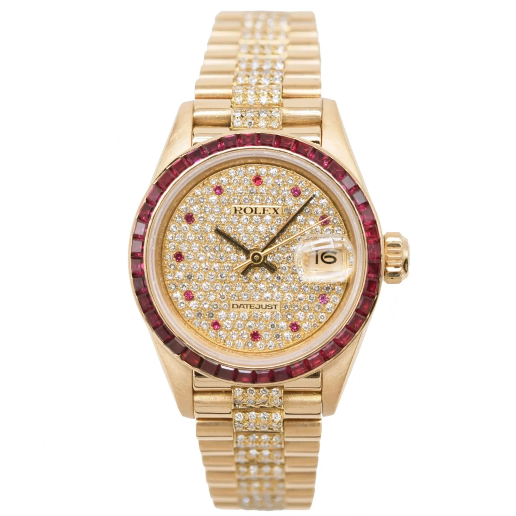 Gold Rolex Datejust 69098 watch with diamond-studded face and band, ruby bezel, and date display at 3 o’clock.