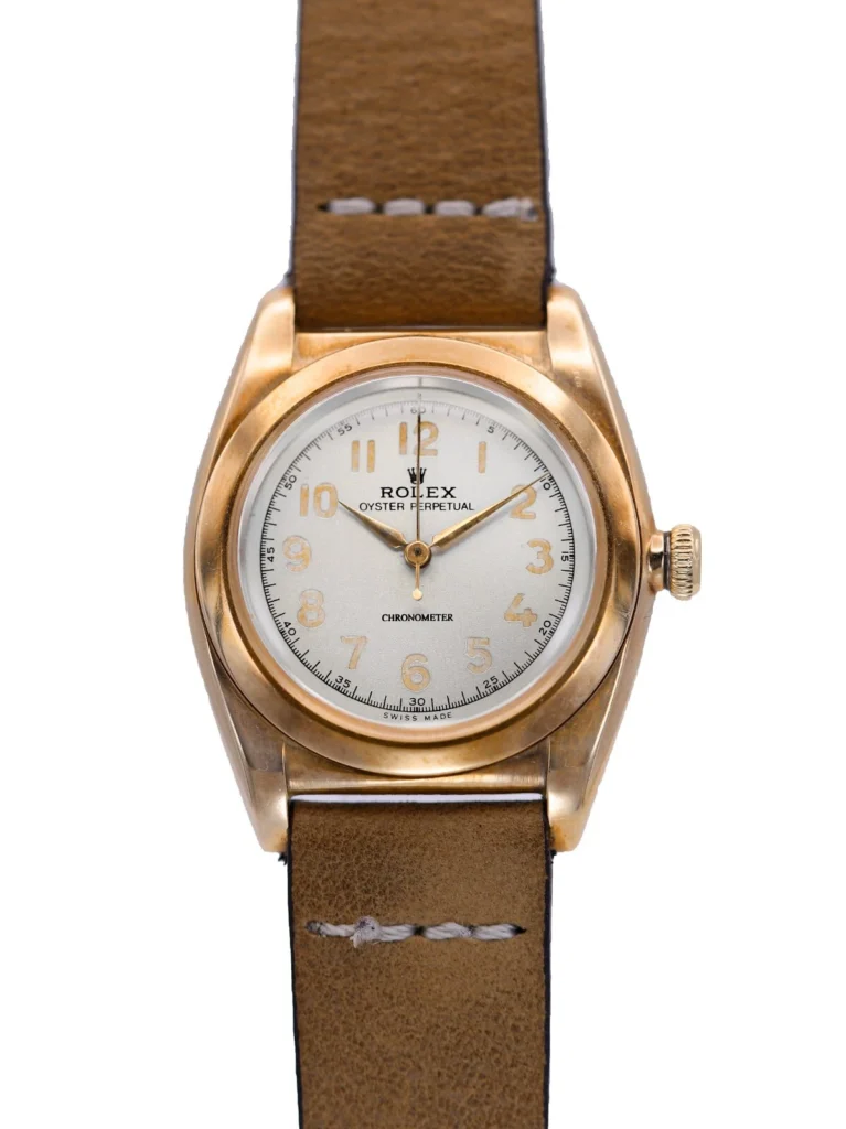 A vintage Rolex Oyster Perpetual watch featuring the classic 3131 movement, with a brown leather strap and an elegant gold case.
