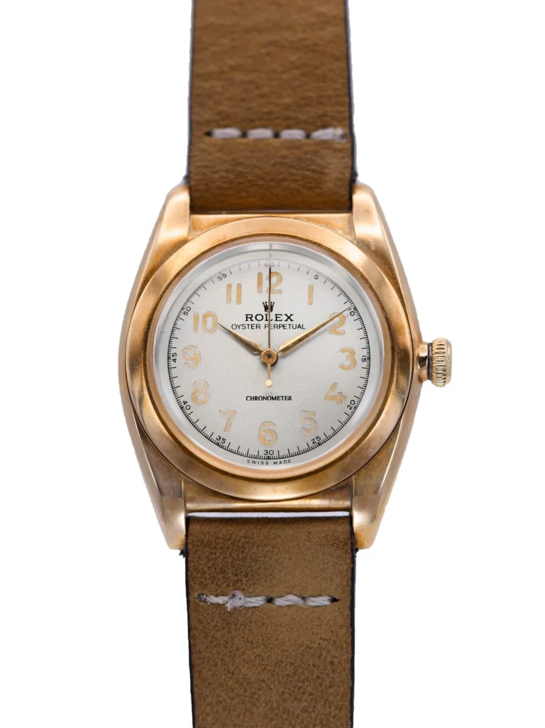 A vintage Rolex Oyster Perpetual watch featuring the classic 3131 movement, with a brown leather strap and an elegant gold case.