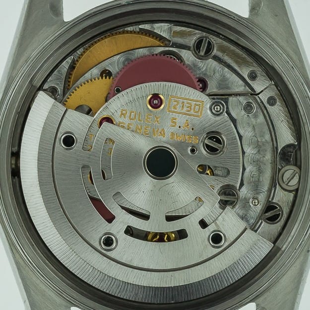 Close-up of a Rolex watch movement showing gears and engraved Rolex S.A. Geneva Swiss 2130 on the mechanism.