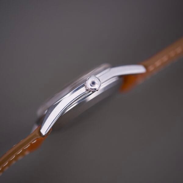 Side view of the Omega Automatic Seamaster 2802 Cross Hair Waffle Dial with a silver case and brown leather strap on a plain background.