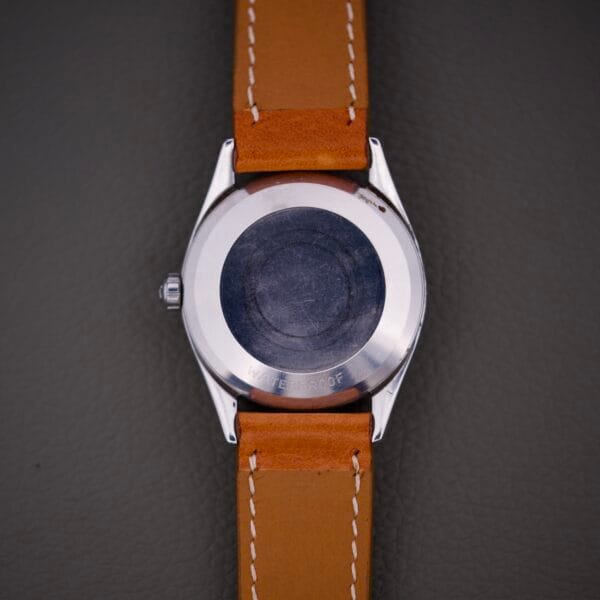 The Omega Automatic Seamaster 2802 Cross Hair Waffle Dial wristwatch, shown face down with a tan leather strap, displays its stainless steel back and features a classic automatic design.