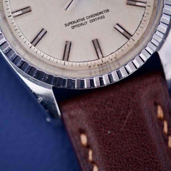 Close-up of a Rolex Datejust 1603 Silver Dial Alpha hands with a brown leather strap and Superlative Chronometer Officially Certified on the dial.