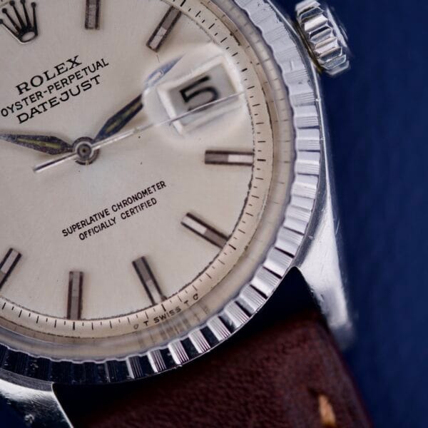 Close-up of a Rolex Datejust 1603 Silver Dial Alpha hands with part of a brown leather strap and detailed bezel visible.