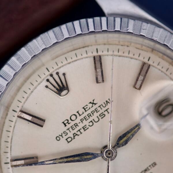 Close-up of the Rolex Datejust 1603 Silver Dial with Alpha hands, highlighting the logo, hour markers, part of the silver dial, and date window.
