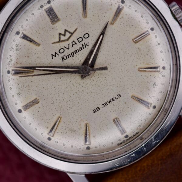 Close-up of the Movado Kingmatic Ref. 15051 28 Jewels watch face, featuring silver hands and markers with a touch of aging; 28 Jewels is discreetly noted on the dial, emphasizing its timeless vintage charm.