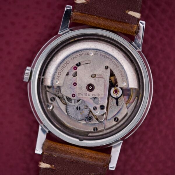 Close-up of the Movado Kingmatic Ref. 15051 28 Jewels watch movement, highlighting its intricate gears and paired with a brown leather strap.