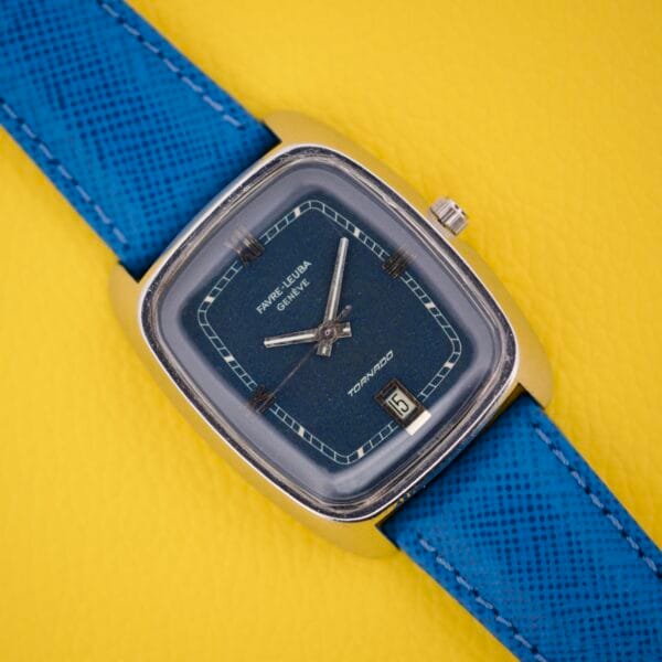 The Favre Leuba Tornado Blue Dial Automatic Date watch, featuring a blue strap and square case, rests on a yellow textured background.