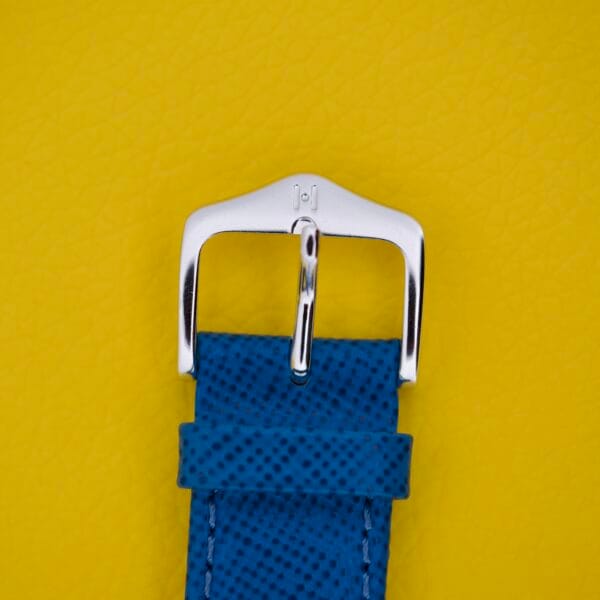 Blue textured watch strap with a silver buckle, inspired by Favre Leuba Tornado Blue Dial Automatic Date, displayed on a bright yellow background.