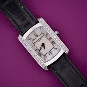 Baume & Mercier Hampton 65504 watch with Mother of Pearl dial, diamond bezel, and black leather strap displayed on a purple textured surface.