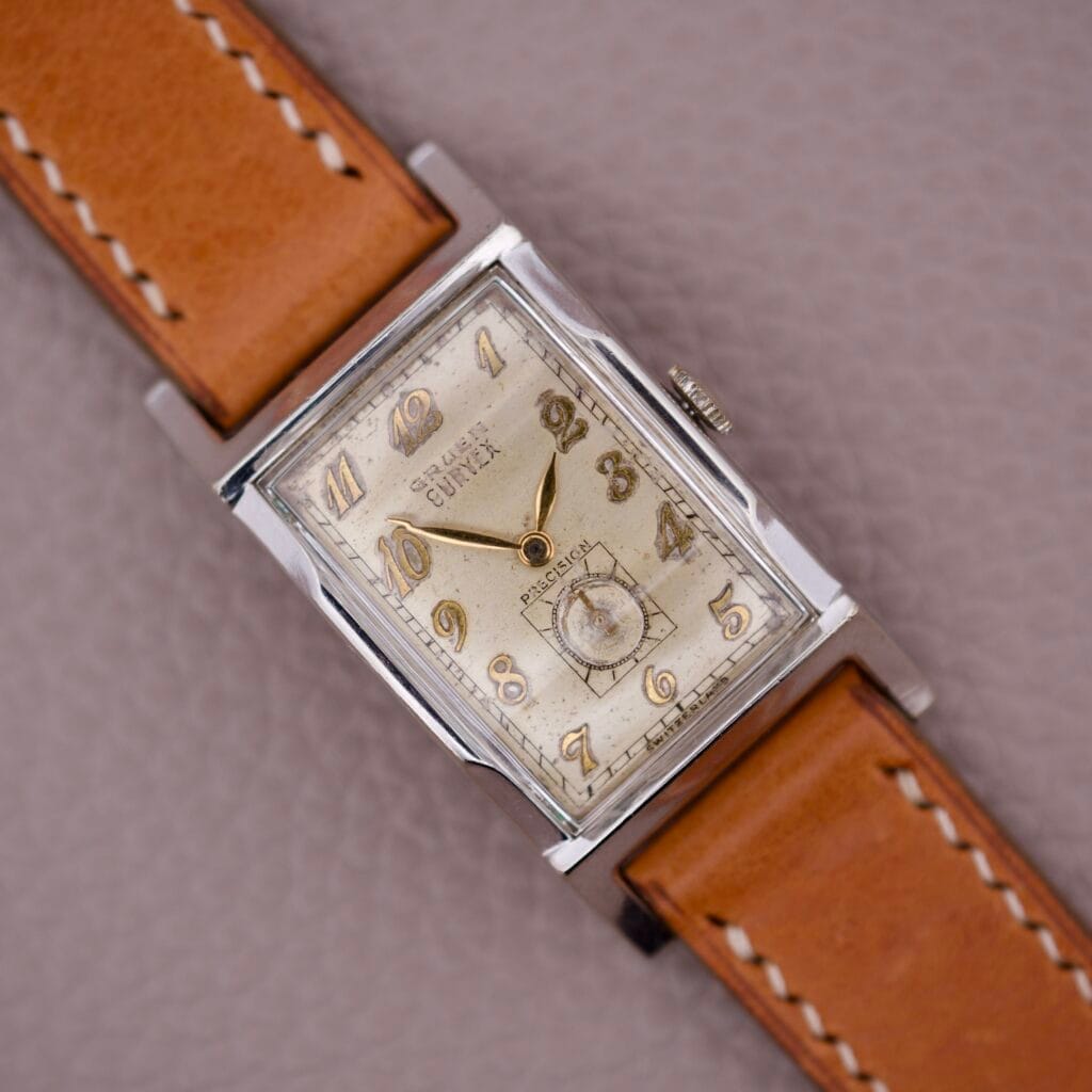 Gruen Curvex Precision Ref. 370-650 Art Deco Tank wristwatch with tan leather strap on a textured light brown surface, highlighting its classic rectangular vintage design.