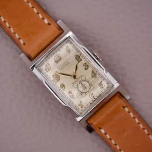 Gruen Curvex Precision Ref. 370-650 Art Deco Tank wristwatch with tan leather strap on a textured light brown surface, highlighting its classic rectangular vintage design.