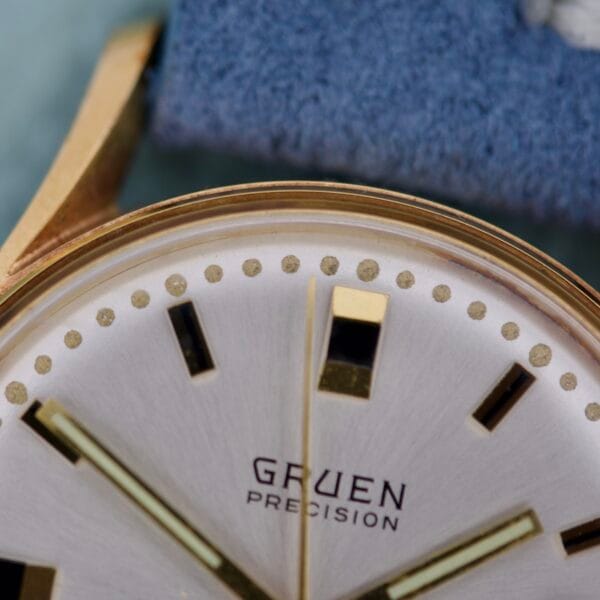 Close-up of the Gruen Precision Date 510RSS CA Sunburst Dial watch face, showcasing gold hour markers and hands on its striking sunburst dial.