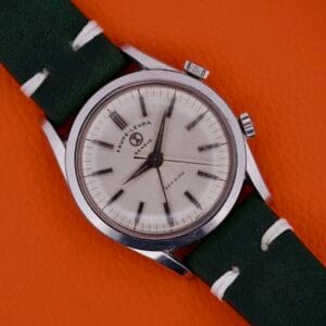 Favre Leuba Geneve Seabird Alarm Stainless Steel wristwatch with green strap, displayed on an orange textured background.