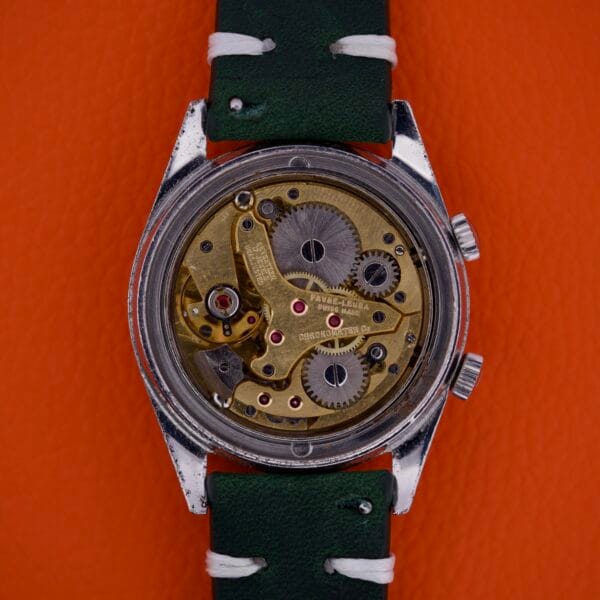 Back view of the Favre Leuba Geneve Seabird Alarm Stainless Steel wristwatch with exposed mechanical gears, a stainless steel case, green strap, and set against an orange background.