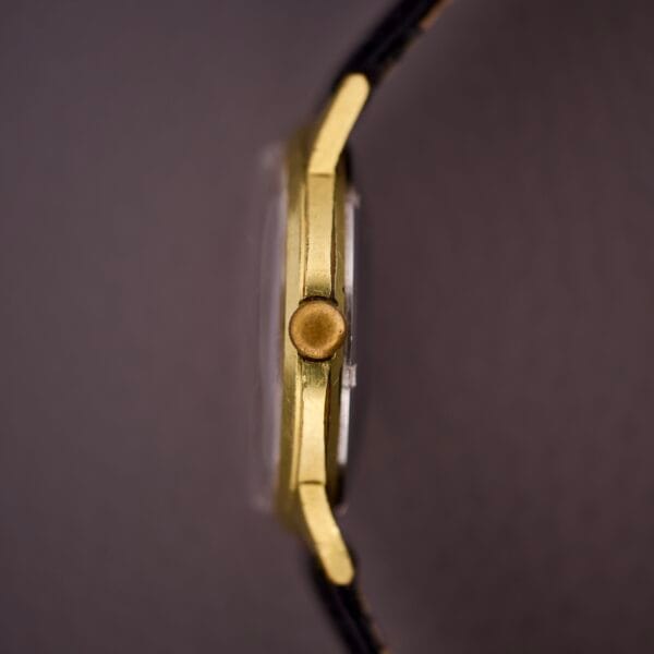 Side view of the Gruen Precision 25 Jewels Autowind Sunburst Dial wristwatch with a black strap, focusing on the crown. The blurred background accentuates its elegant sunburst dial and refined automatic craftsmanship.
