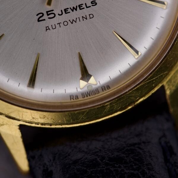 Close-up of the Gruen Precision 25 Jewels Autowind Sunburst Dial watch face, highlighting its gold finish and SWISS markings.