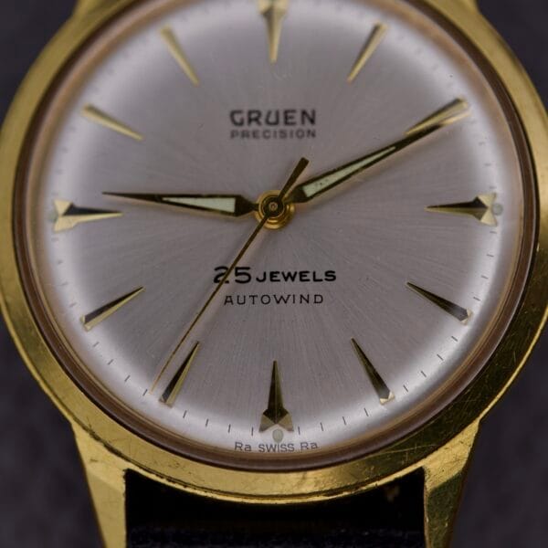 Close-up of a Gruen Precision 25 Jewels Autowind watch featuring a sunburst dial and black leather strap.