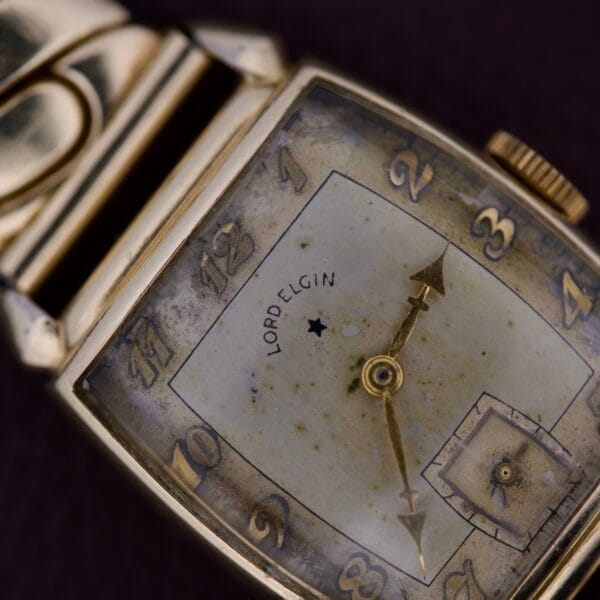 Close-up of a vintage Lord Elgin Art Deco Caliber 559 wristwatch, featuring a square face and visible dial wear; 21 jewels, made in the USA.