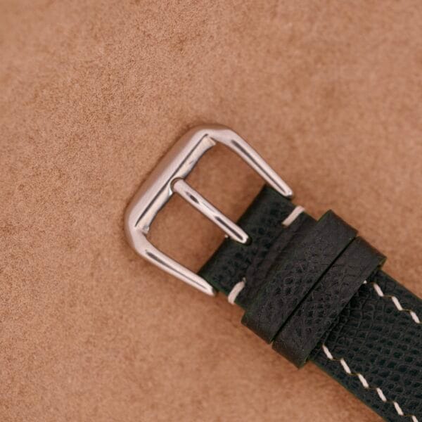 Close-up of a black leather Wyler Dynawind Heavy Duty 660 Life Guard watch strap with a silver buckle, resting on a tan textured surface.