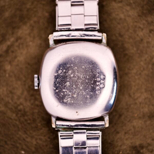 The back of a Tudor Cushion Case Trench Watch Circa 1930s, silver with a metal band and cushion case, features the number 681879 engraved on it.