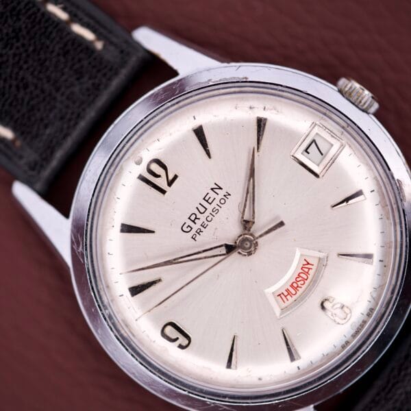 Close-up of a Gruen Precision Day / Date 522 RSS Sunburst Dial wristwatch, displaying the time 8:23 with day (Thursday) and date windows.