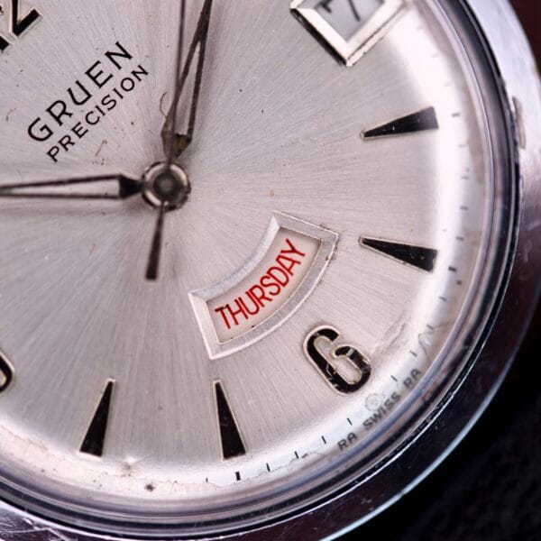 Close-up of the Gruen Precision Day / Date 522 RSS Sunburst Dial watch, featuring a striking sunburst dial and displaying Thursday in red above the 6 oclock position.